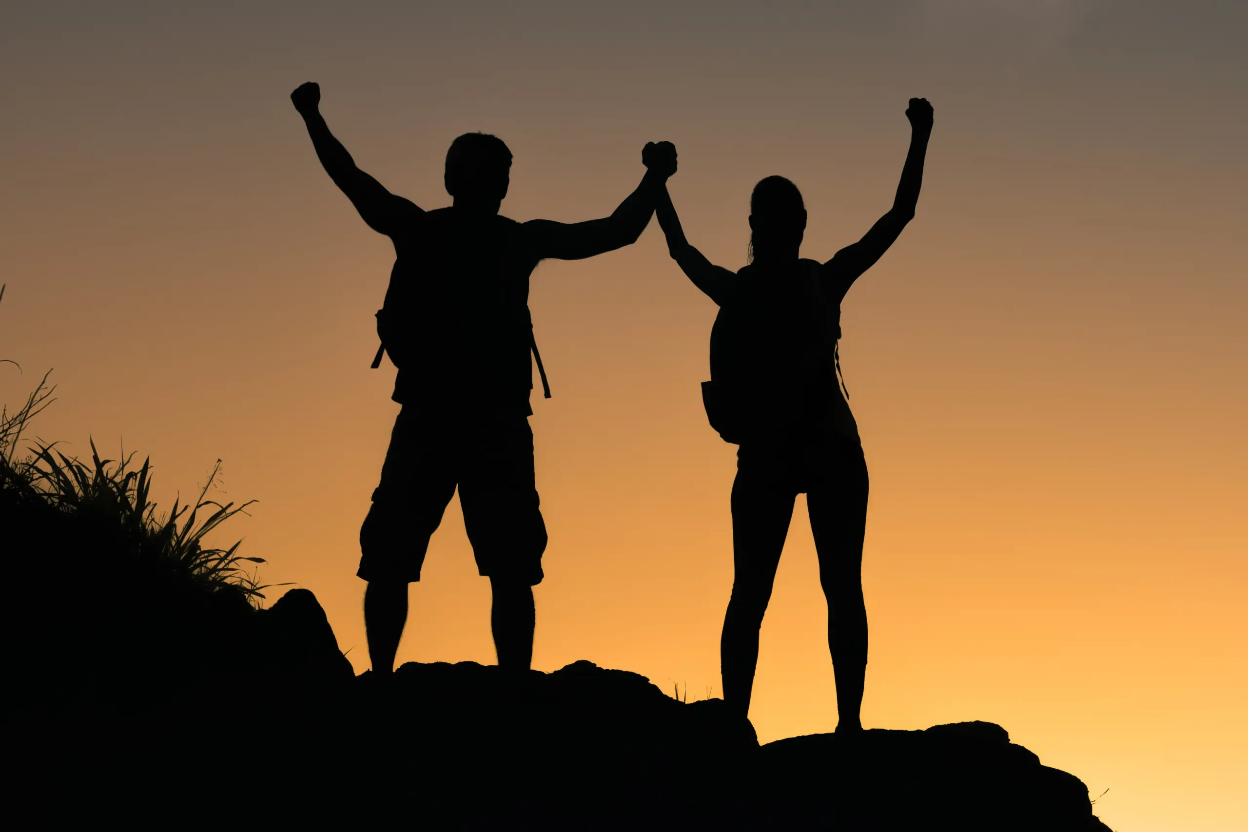 A couple on a mountaintop silhouetted by the sunset flex their arms. Schedule Amino Blend IV Therapy from Balanced Medical Solutions in San Francisco Bay Area.