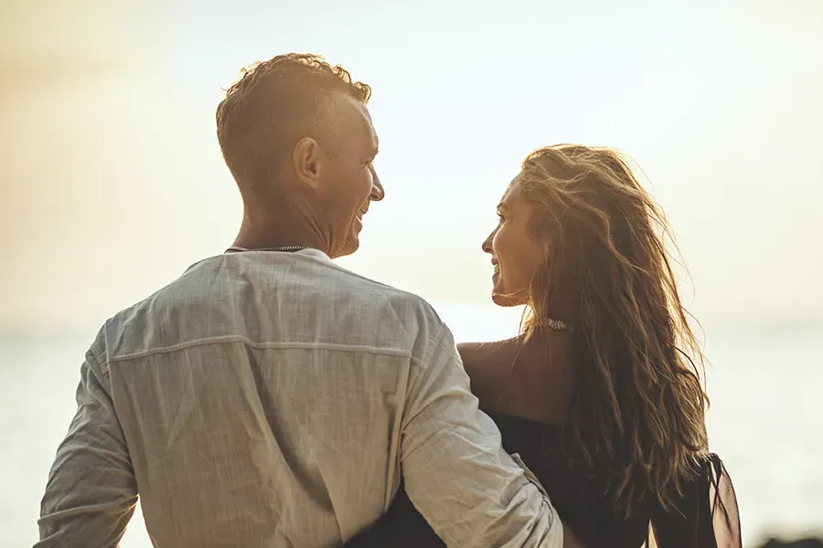 A couple gazes at each other on the beach at sunrise, viewed from behind. Schedule Anti-Aging treatment from Balanced Medical Solutions in San Francisco Bay Area.
