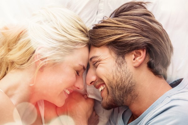 A couple laugh with each other and touch foreheads in bed. Schedule Ascorbic Acid IV Therapy from Balanced Medical Solutions in San Francisco Bay Area.