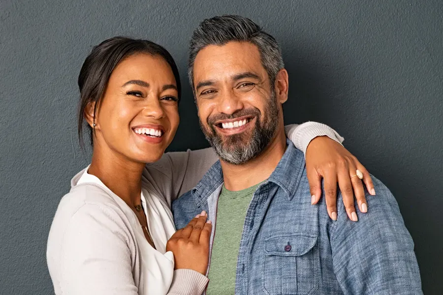 Bioidentical-Hormone-Therapy-Doctor A middle-aged couple with their arms around each other standing against a gray background and smiling, happy with the bioidentical hormone therapy they received from Balanced Medical Solutions in San Francisco Bay Area.