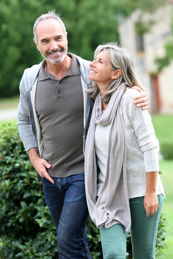 Bioidentical-Hormone-Therapy-Treatment A mature couple in gray toned clothes and jeans walk happily outside, happy with their successful bioidentical hormone treatments from Balanced Medical Solutions in San Francisco Bay Area.