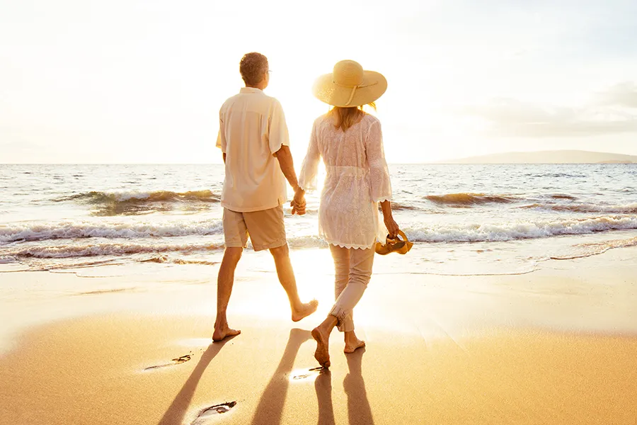 A middle-aged couple walk on a sunny beach. Get Coenzyme Q-10 Antioxidant IV Therapy from Balanced Medical Solutions in San Francisco Bay Area.