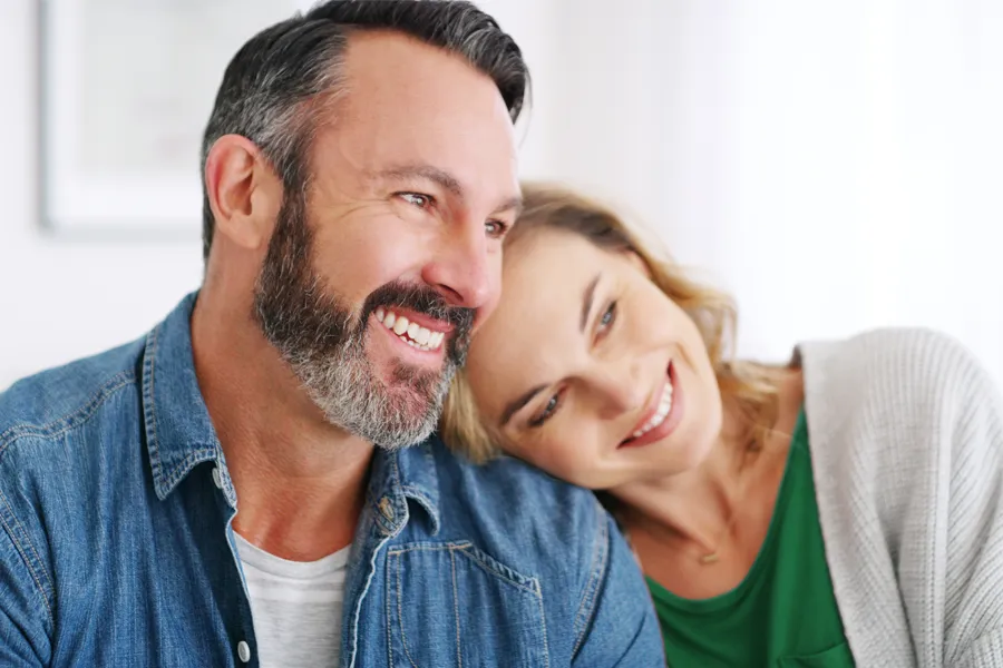 A middle-aged white couple in a bright white room smile and lay their heads on each other. Schedule concierge health and wellness services from Balanced Medical Solutions in San Francisco Bay Area.