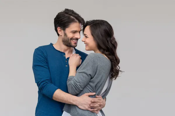 A man in a blue shirt embracing a woman in a gray shirt smiles due to his successful erectile dysfunction care from Balanced Medical Solutions in San Francisco Bay Area.