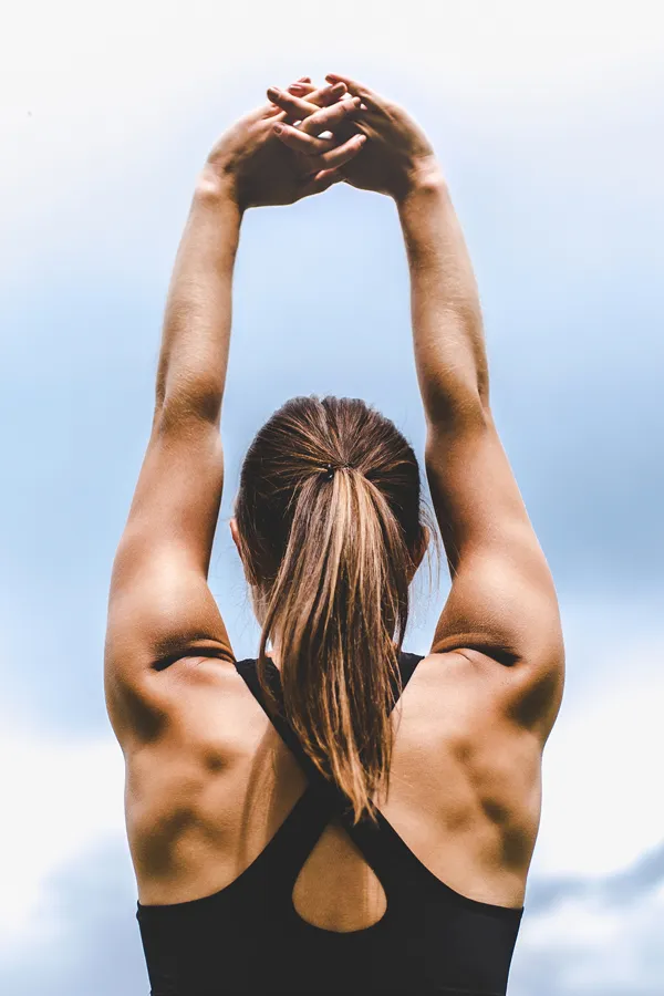 A toned woman seen from behind stretching her arms into the air. Get GLP-1 Weight Loss Injections from Balanced Medical Solutions in San Francisco Bay Area.