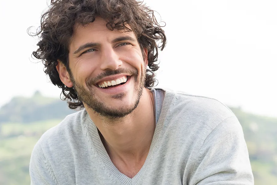 Hair-Loss-Clinic A man with radiant curly hair and a confident smile looks to the horizon. Balanced Medical Solutions in San Francisco Bay Area offers effective therapies to support hair regrowth and scalp health to treat hair loss.