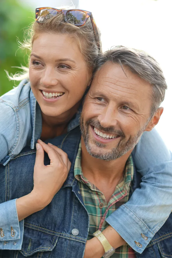 A couple in denim jackets embrace playfully outdoors. Get hypogonadism treatment from Balanced Medical Solutions in San Francisco Bay Area.