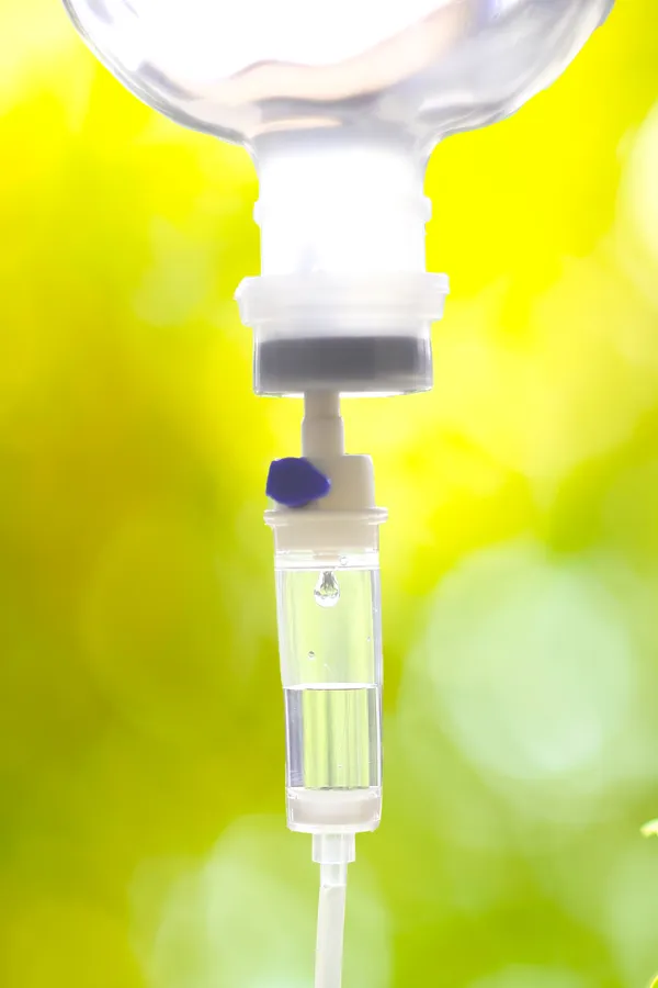 NAD-Therapy-Treatment Close up of an IV drip with a lush, green background. Get NAD Therapy from Balanced Medical Solutions in San Francisco Bay Area.