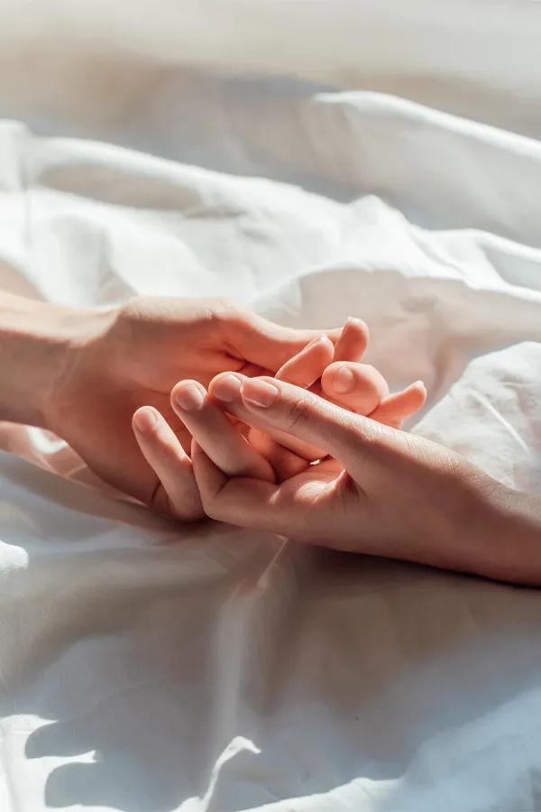 A close up of a man and woman's hands lightly clasping on a bedsheet, representing successful PT141 sexual wellness treatment for women from Balanced Medical Solutions in San Francisco Bay Area.