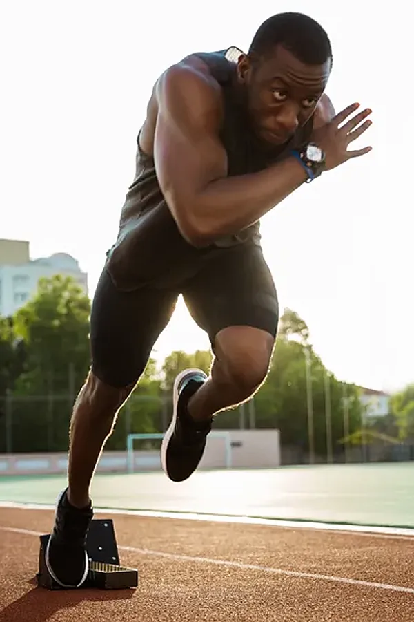 A black athlete bounding off of the starting block on a track. Get performance optimization treatment from Balanced Medical Solutions in San Francisco Bay Area.