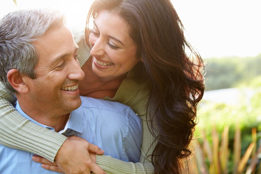 Regenerative-Exosome-IV-Therapy-Clinic A middle-aged latin couple embrace playfully in a green field. Get regenerative exosome IV therapy from Balanced Medical Solutions in San Francisco Bay Area.