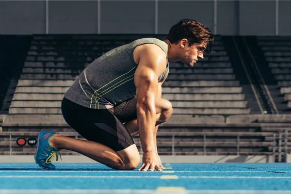 Sermorelin-Clinic With a determined look, Aamuscular man in track clothes kneels at the start of a race. Get Sermorelin peptide therapy from Balanced Medical Solutions in San Francisco Bay Area.
