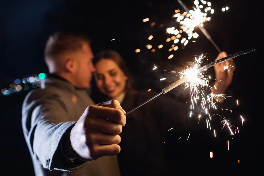 A couple in coats embrace and hold out sparklers at night, representing shockwave treatment for erectile dysfunction from Balanced Medical Solutions in San Francisco Bay Area.