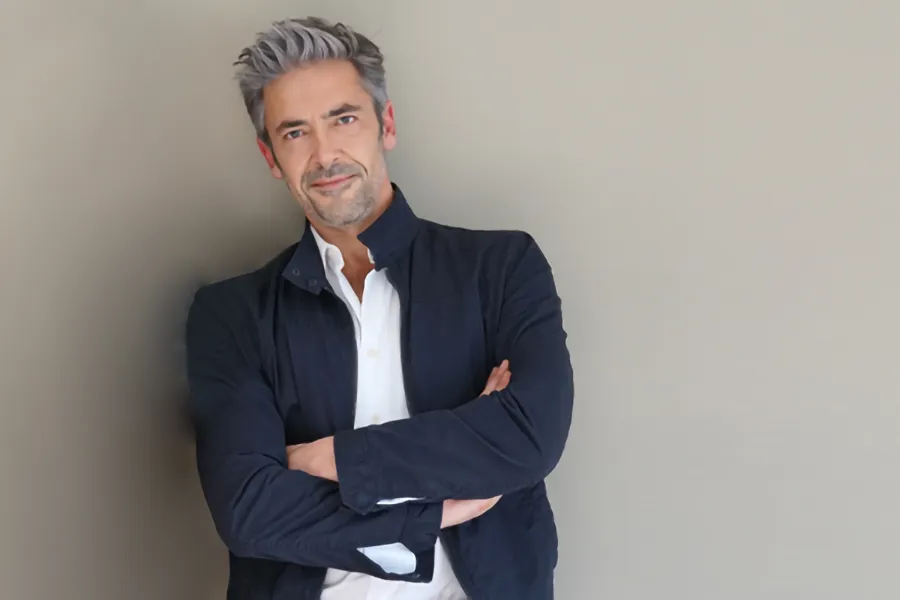 Testosterone-Low-T-Solutionsn-Clinic A middle-aged man in a white shirt and dark blue jacket leans against a gray wall smiling. Get testosterone for Low T from Balanced Medical Solutions in San Francisco Bay Area.