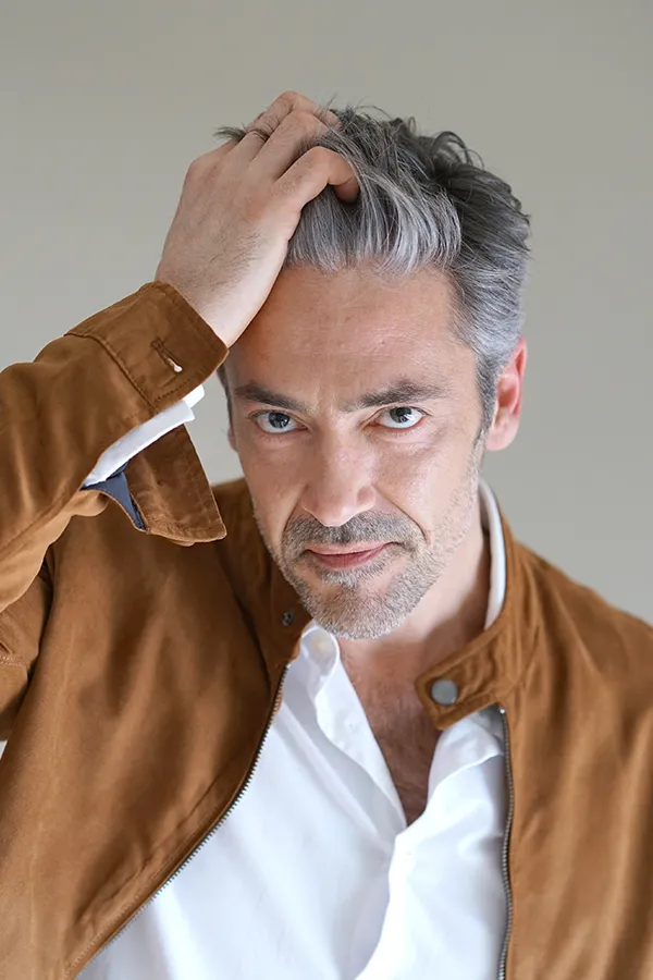 A middle-aged man runs his hand through his thick, healthy hair. Get stem cells and exosomes for hair restoration from Balanced Medical Solutions in San Francisco Bay Area.